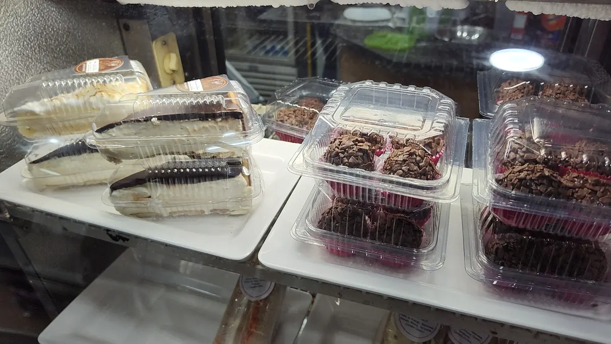 Vitrine com fatias de torta e brownies embalados